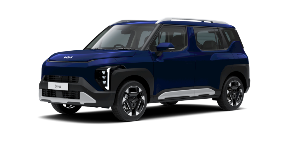 A sleek and modern KIA Syros SUV parked on a scenic Greek coastline, showcasing its elegant curved front design and boxy rear.