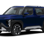 A sleek and modern KIA Syros SUV parked on a scenic Greek coastline, showcasing its elegant curved front design and boxy rear.