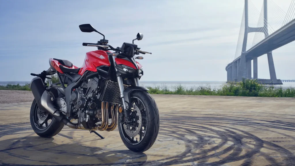 Side view of the 2025 Honda CB1000 Hornet SP in Matte Ballistic Black Metallic with gold accents, showcasing its aggressive streetfighter design, LED headlight, and chiselled 17-litre fuel tank, parked on an urban street in India.